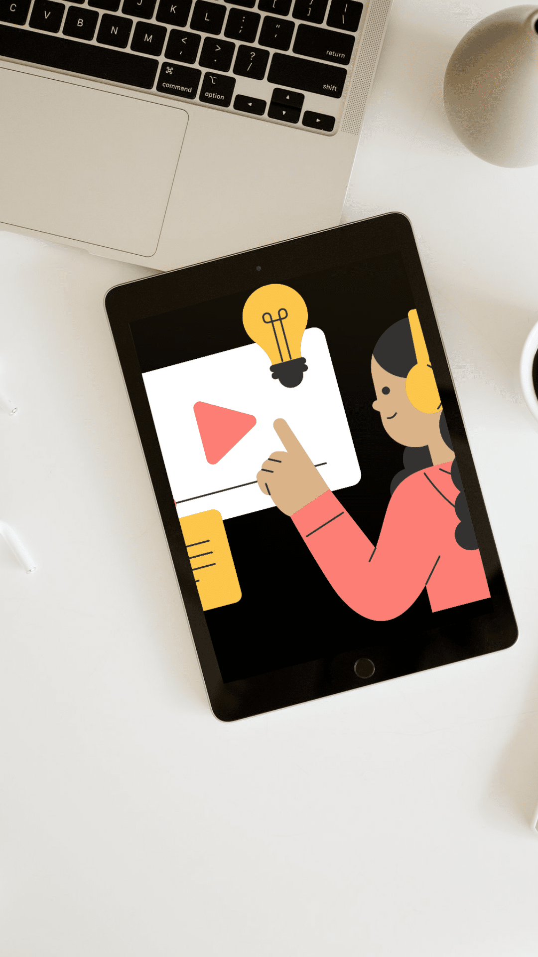 Tablet screen showing online learning illustration with play button and idea icon, e-learning concept on white desk next to laptop. Tablet képernyőjén online tanulási illusztráció, play gomb és ötlet ikon, e-learning koncepció fehér asztalon laptop mellett. InnovaTeQ